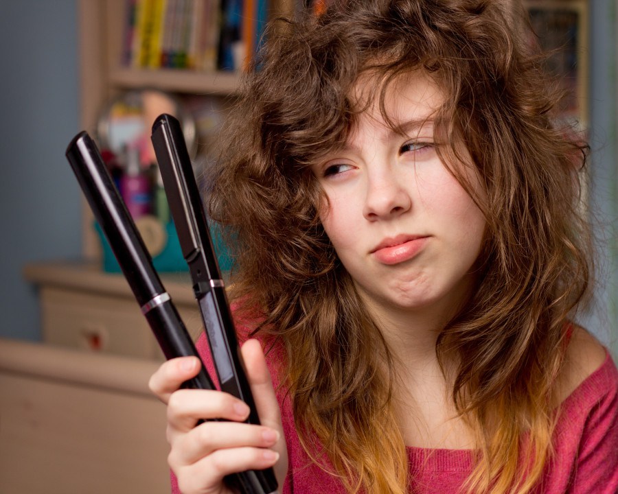 teenage girl with messy hair and flatiron straightener